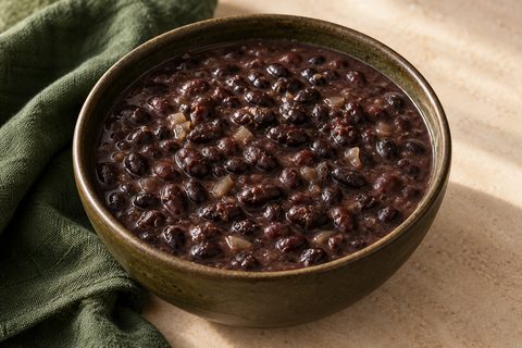 Black beans in dark broth with softened onion, in a ceramic bowl