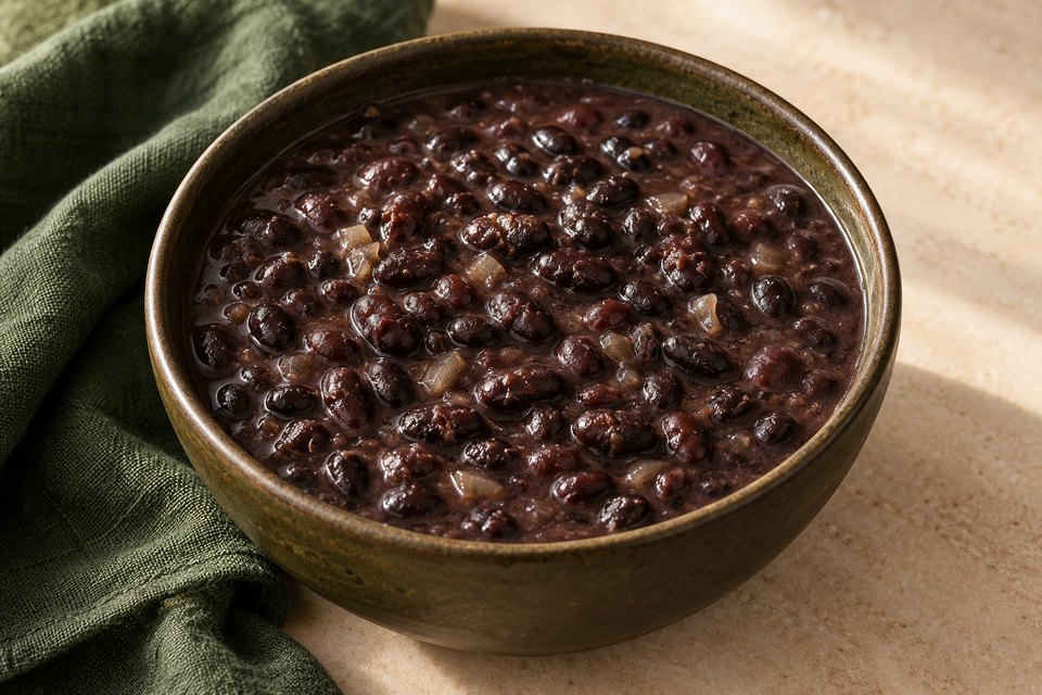 Black beans in dark broth with softened onion, in a ceramic bowl